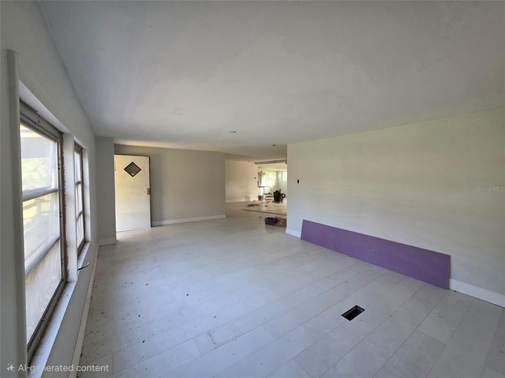 An unfinished room features light-colored flooring, white walls, a purple board, and a doorway — 37414 NORTHSIDE DRIVE, ZEPHYRHILLS, FL