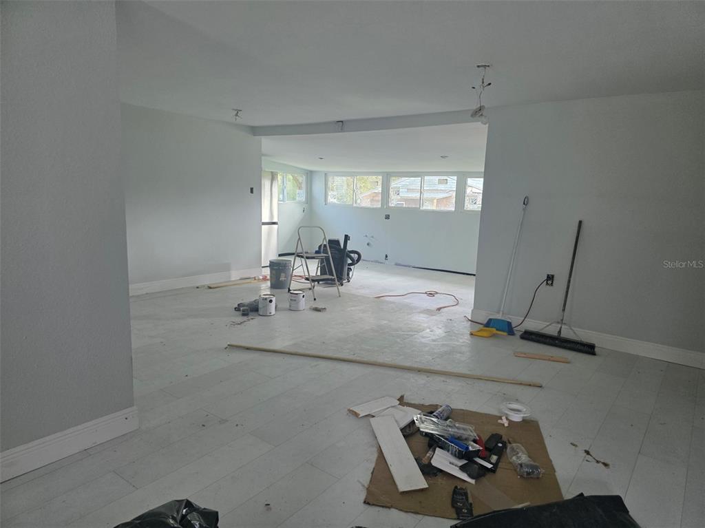 An unfinished room with light-colored flooring, gray walls, and a step-down area with windows — 37414 NORTHSIDE DRIVE, ZEPHYRHILLS, FL