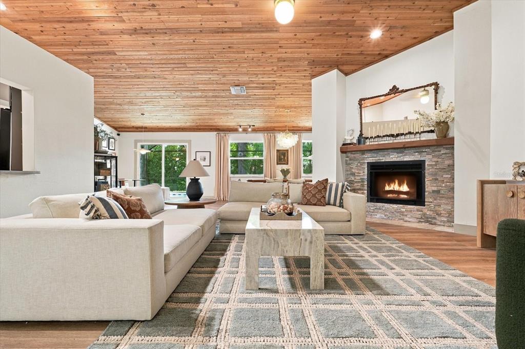 A living room features a wood-paneled vaulted ceiling, a stone fireplace, and a large rug — 1515 MIDNIGHT PASS WAY, CLEARWATER, FL