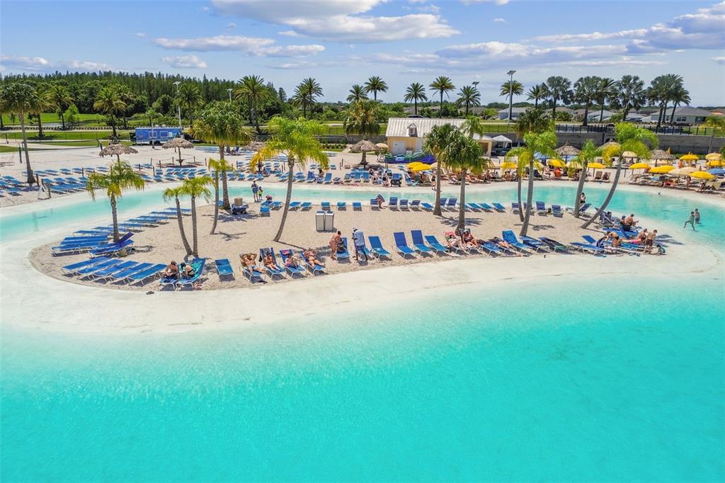 An aerial view shows a turquoise swimming lagoon surrounding a sandy island with palm trees — 31840 SAPNA CHIME DRIVE, WESLEY CHAPEL, FL
