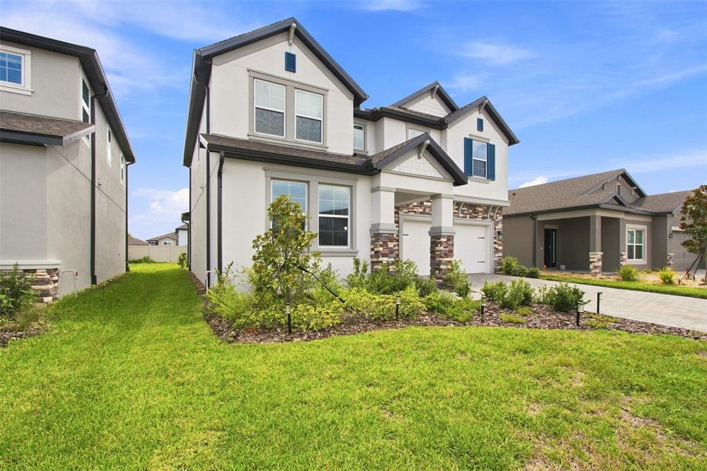 A two-story suburban house with a stucco exterior, stone accents, and a two-car garage — 31840 SAPNA CHIME DRIVE, WESLEY CHAPEL, FL