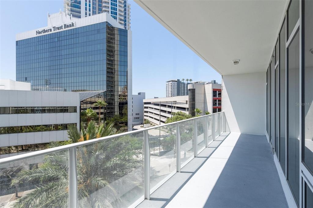 A balcony with a glass railing overlooks a city street and a Northern Trust Bank building — 175 1ST STREET S UNIT 504, ST PETERSBURG, FL