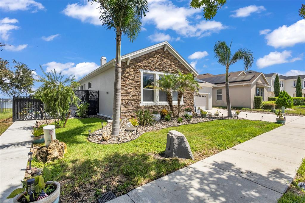 A single-story house with a stone facade, palm trees, and a landscaped front yard — 237 BLUE CYPRESS DRIVE, GROVELAND, FL