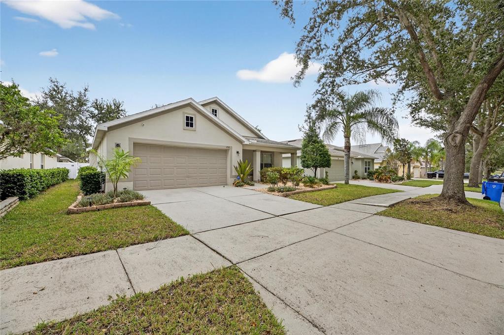 A single-story suburban house with a beige exterior, a two-car garage, and a concrete driveway — 424 DOWN PINE DRIVE, SEFFNER, FL