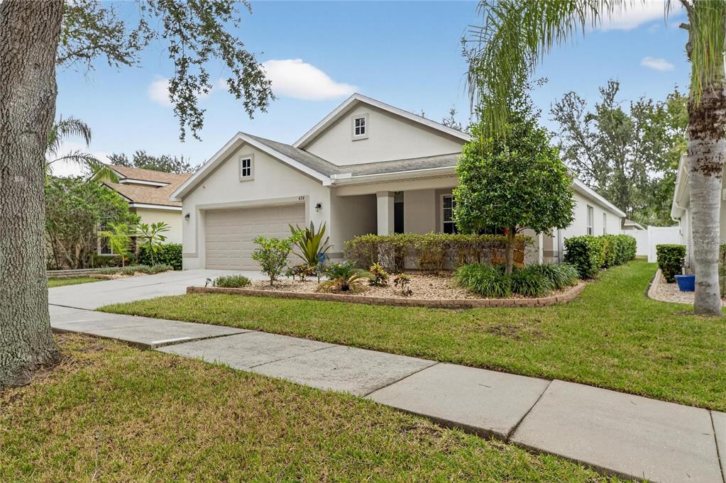 A single-story house with a beige exterior, a two-car garage, and a landscaped front yard — 424 DOWN PINE DRIVE, SEFFNER, FL