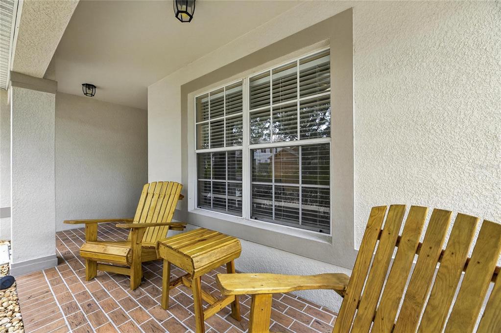 A covered porch features a brick floor, two wooden chairs, and a small side table — 424 DOWN PINE DRIVE, SEFFNER, FL