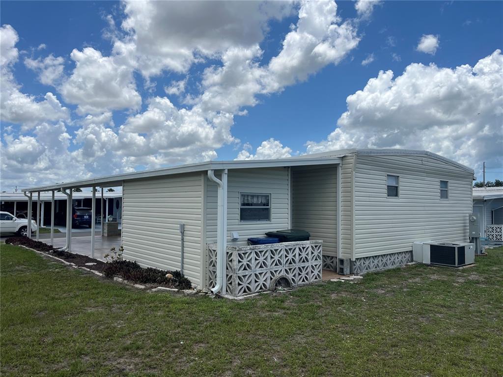 The exterior of a light-colored mobile home features a carport and decorative concrete block skirting — 824 TRENTO, VENICE, FL