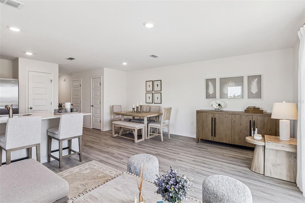 A bright, open-concept living and dining area features light wood flooring and neutral furniture — 4707 TONY STREET, LAKE WALES, FL