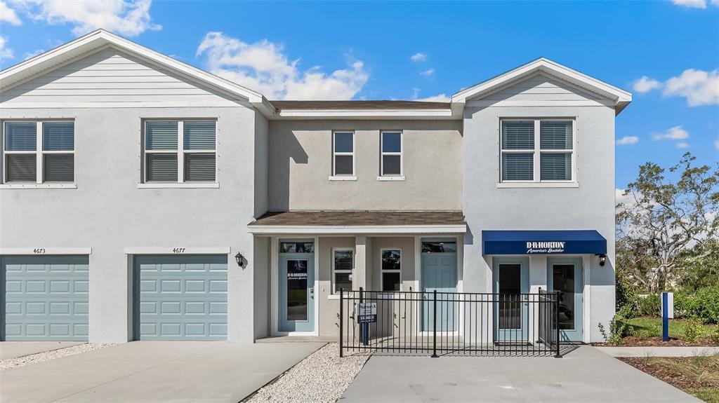 The exterior of a two-story townhouse complex features light gray stucco walls and blue doors — 4677 PLEASANT AVENUE, PALM HARBOR, FL