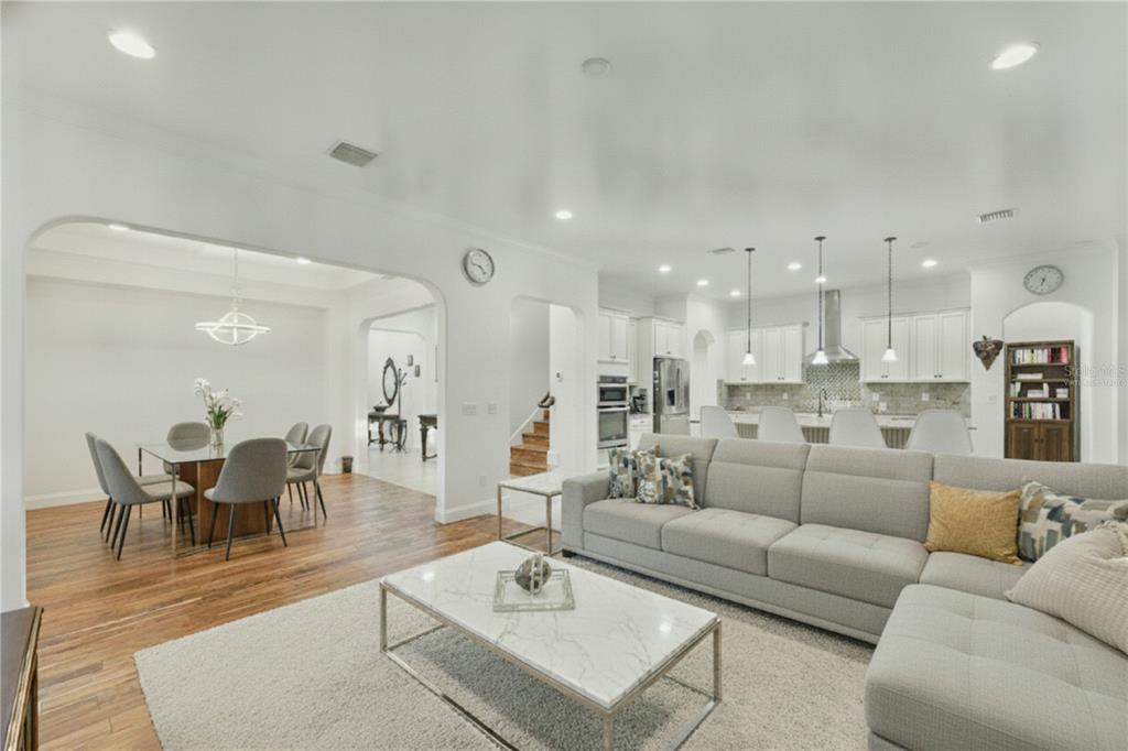 An open-concept living room with a gray sectional sofa, marble coffee table, and adjacent kitchen — 6752 TRELLIS VINE LOOP, WINDERMERE, FL