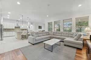 A spacious open-concept living room features a large gray sectional sofa and a modern kitchen — 6752 TRELLIS VINE LOOP, WINDERMERE, FL