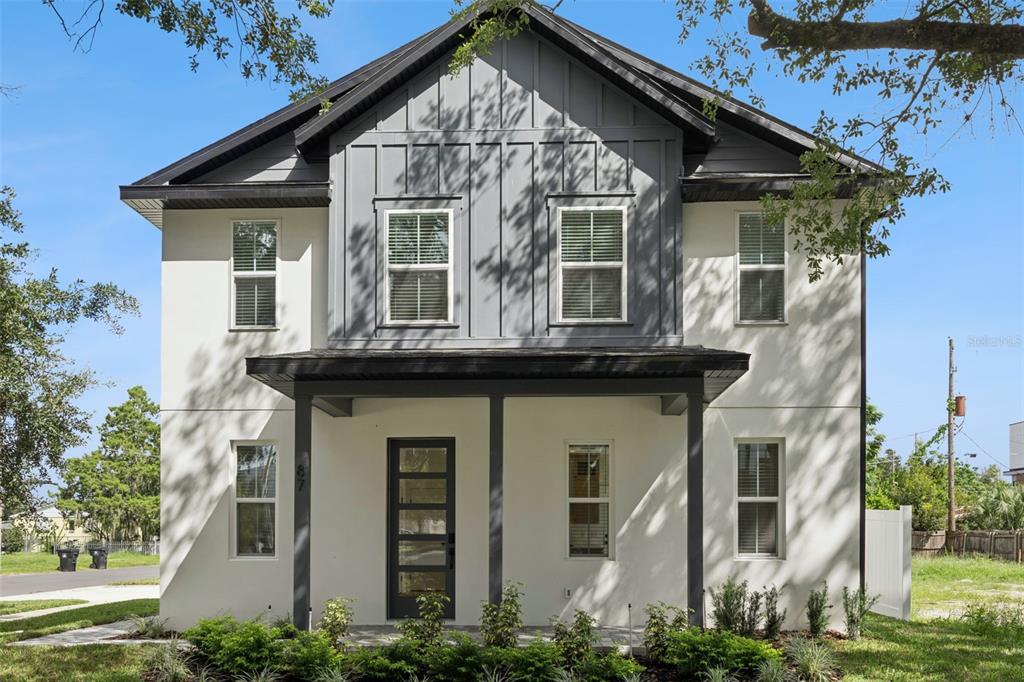 A two-story house with cream stucco siding, dark trim, and a covered front porch — 87 W MURIEL STREET, ORLANDO, FL