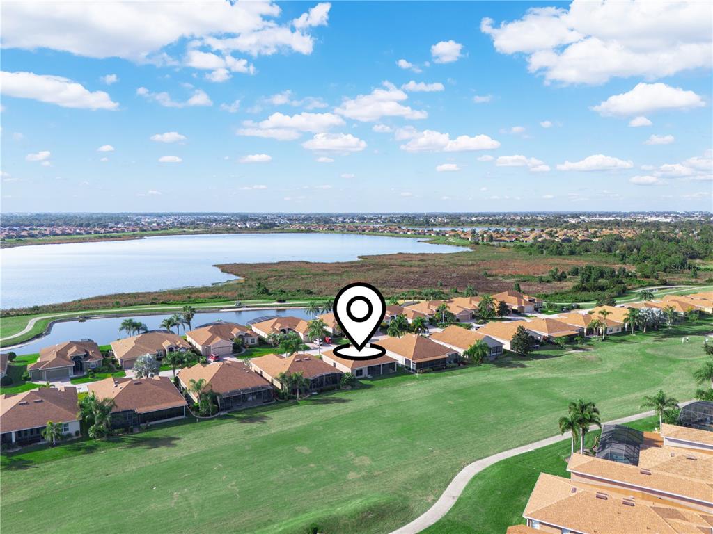 An aerial view shows a residential neighborhood with houses bordering a golf course and lake — 5197 PEBBLE BEACH BOULEVARD, WINTER HAVEN, FL