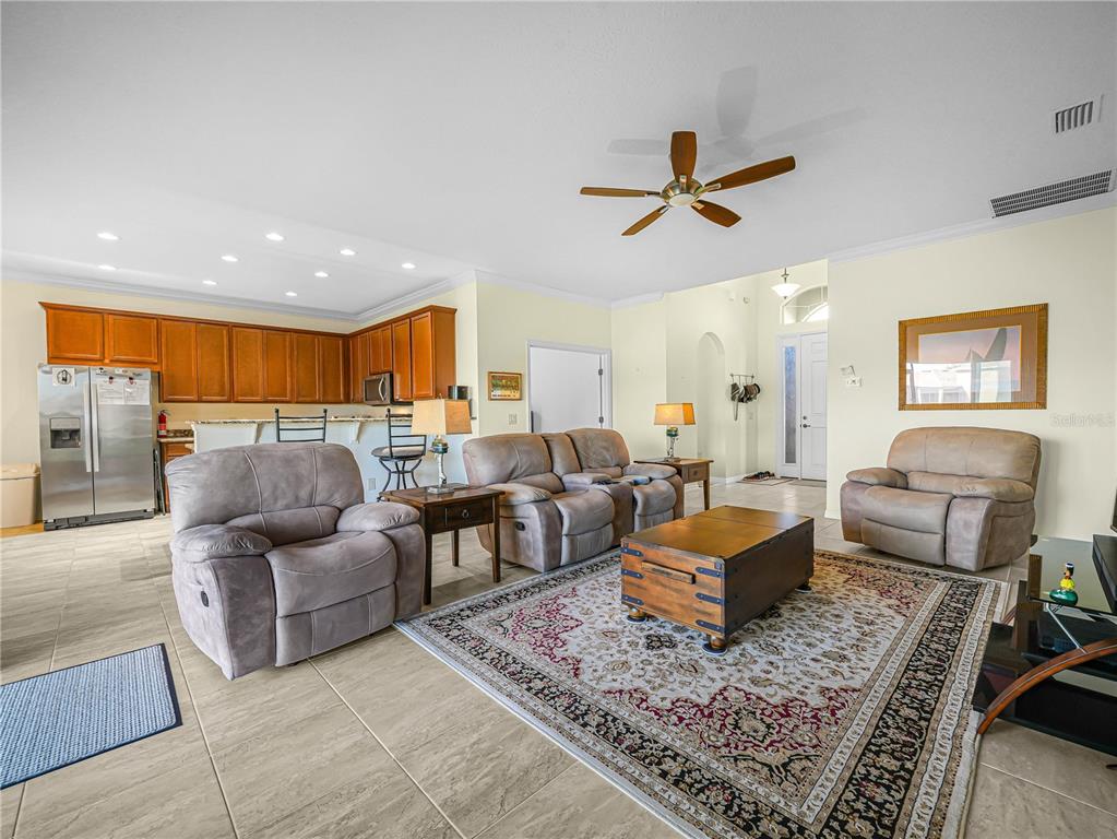 A living room with tile floors, a rug, and a kitchen with wooden cabinets — 5197 PEBBLE BEACH BOULEVARD, WINTER HAVEN, FL
