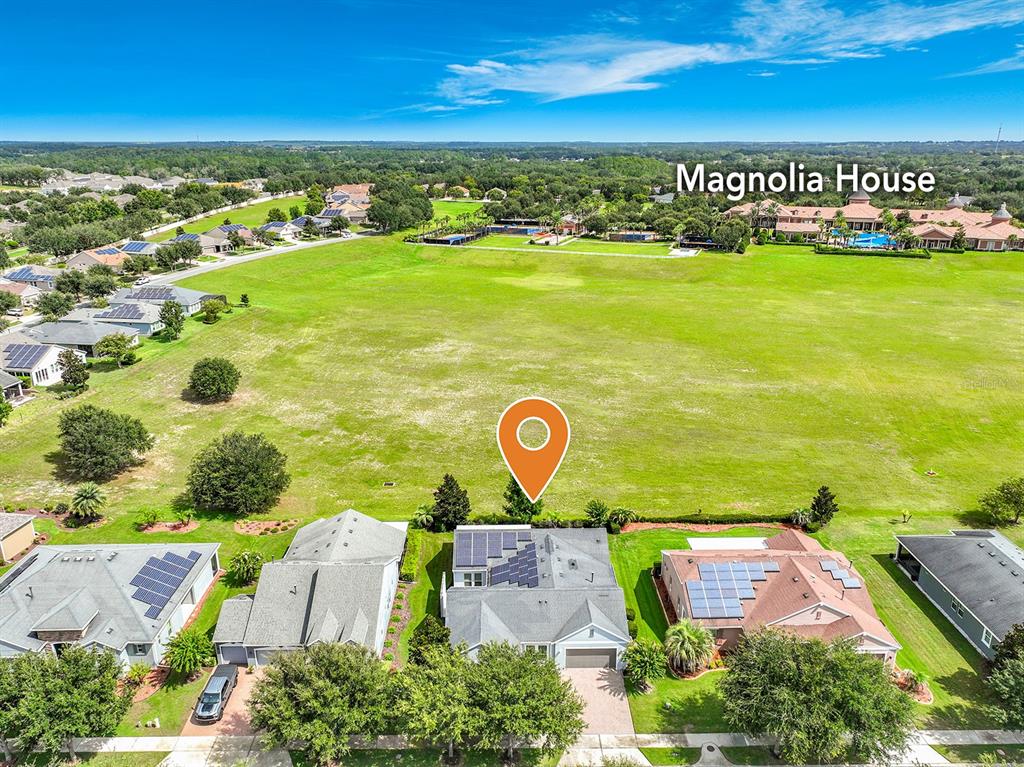 An aerial view shows a residential house with solar panels and a large grassy field — 107 BALMY COAST ROAD, GROVELAND, FL