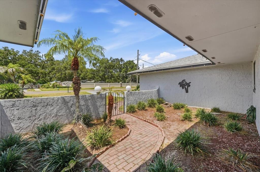 A brick walkway leads through a courtyard with palm trees toward a gated entrance — 543 STATE ROAD 559, AUBURNDALE, FL