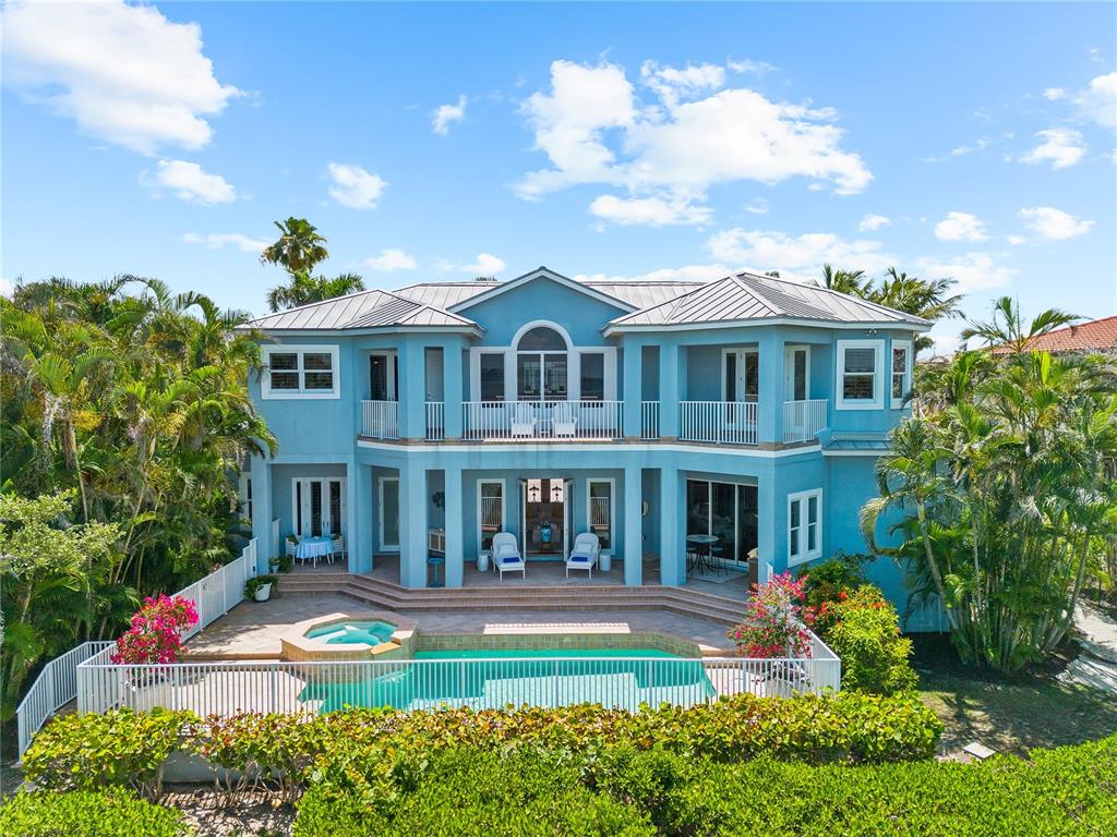 A two-story blue house features a swimming pool, hot tub, and balcony in a tropical setting — 757 HIDEAWAY BAY DRIVE, LONGBOAT KEY, FL