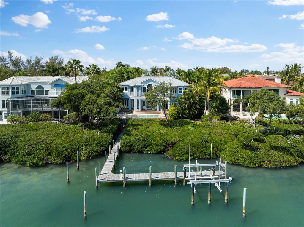 An aerial view shows three waterfront homes with a wooden dock extending into the water — 757 HIDEAWAY BAY DRIVE, LONGBOAT KEY, FL