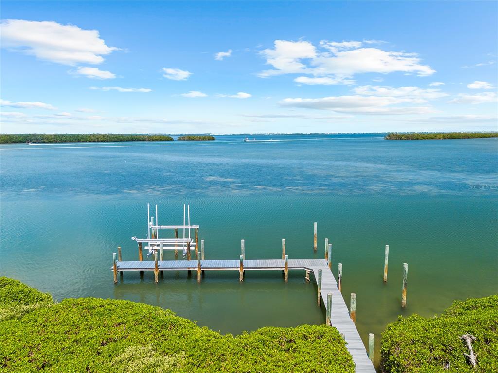 An elevated view of a wooden dock extending into a calm bay with mangroves — 757 HIDEAWAY BAY DRIVE, LONGBOAT KEY, FL