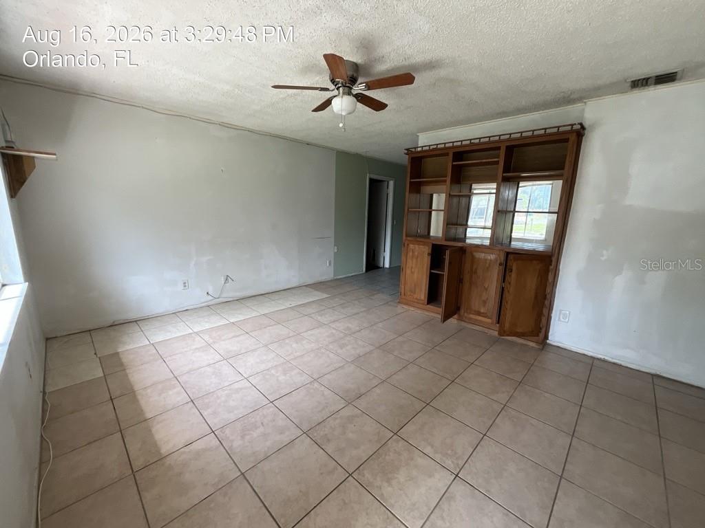 A living room features beige tile flooring, a ceiling fan, and a built-in wooden shelving unit — 4409 WATCH HILL ROAD, ORLANDO, FL