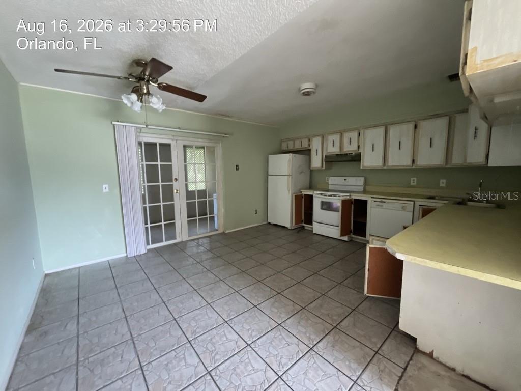 A kitchen with light green walls, white cabinets, tile flooring, and a sliding glass door — 4409 WATCH HILL ROAD, ORLANDO, FL