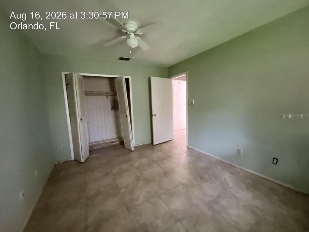 A bedroom with light green walls, tile flooring, a ceiling fan, and an open closet — 4409 WATCH HILL ROAD, ORLANDO, FL