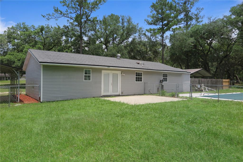 The exterior of a gray-sided house features a concrete patio, French doors, and a pool — 11320 122ND TRAIL, LIVE OAK, FL