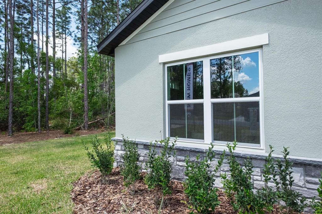 The exterior of a house features light-colored stucco, stone veneer, and a window with trim — 2420 SW 159 LANE, OCALA, FL
