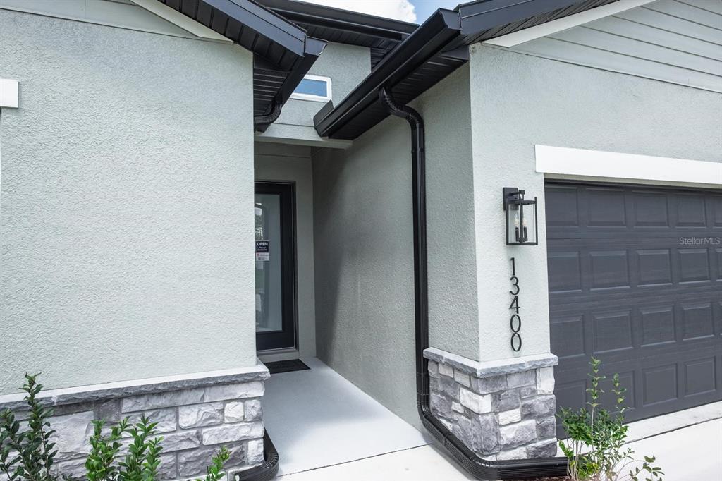 The exterior of a house features a stone-accented facade, a dark garage door, and a recessed entryway — 2420 SW 159 LANE, OCALA, FL
