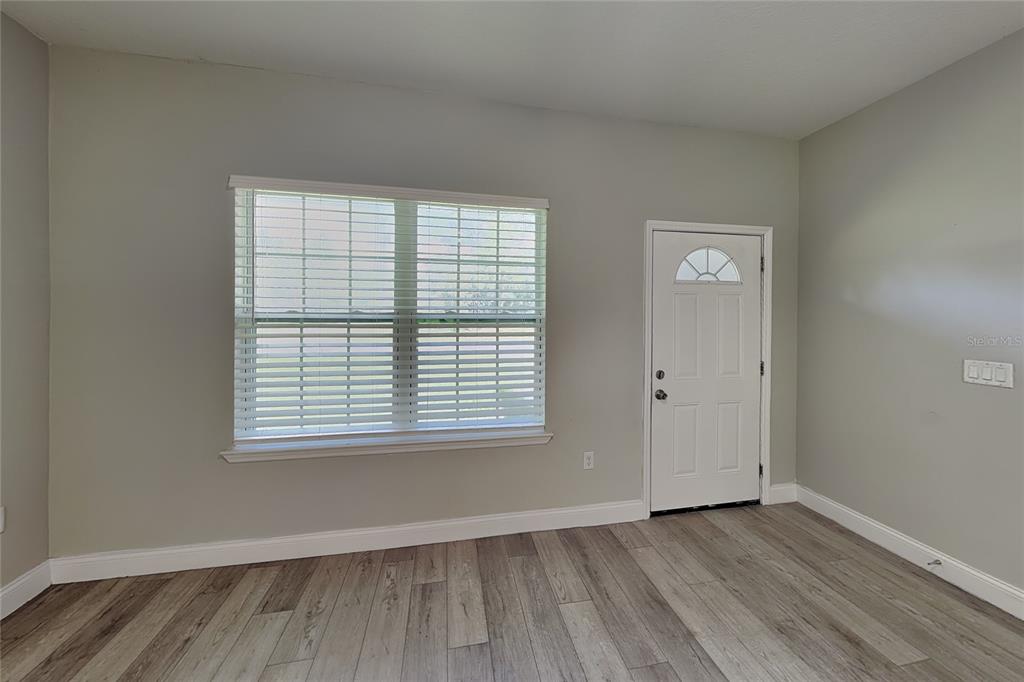 An empty room features light gray walls, wood-look flooring, a window with blinds, and a door — 3212 W MARIE DRIVE, CITRUS SPRINGS, FL