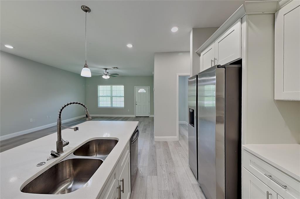 A kitchen island with a double sink overlooks an open-concept living area with light flooring — 3212 W MARIE DRIVE, CITRUS SPRINGS, FL