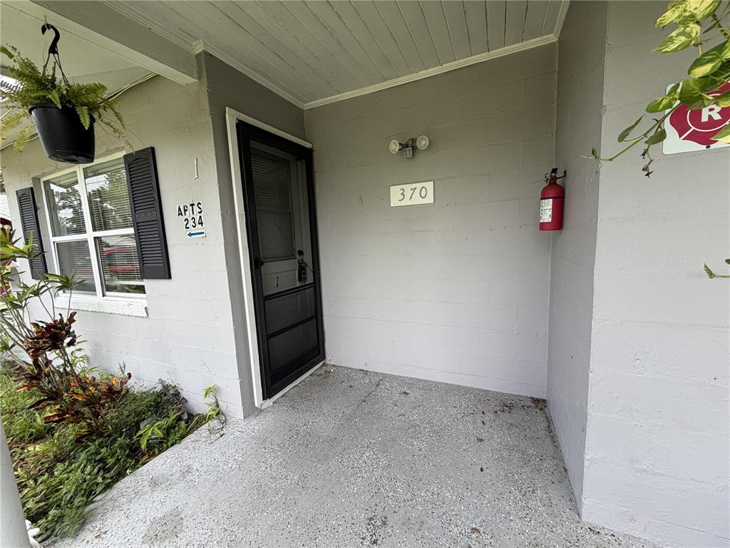 The exterior entrance of a residential unit features a gray concrete wall, a door, and a fire extinguisher — 370 3RD STREET NW, LARGO, FL