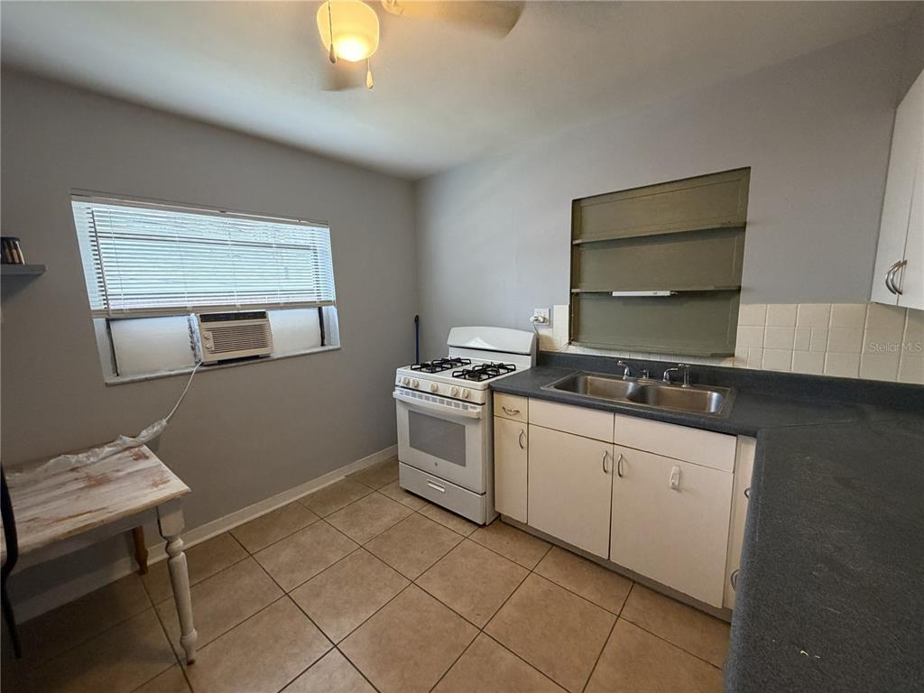 A kitchen features white cabinets, a gas stove, a double sink, and tiled flooring — 370 3RD STREET NW, LARGO, FL