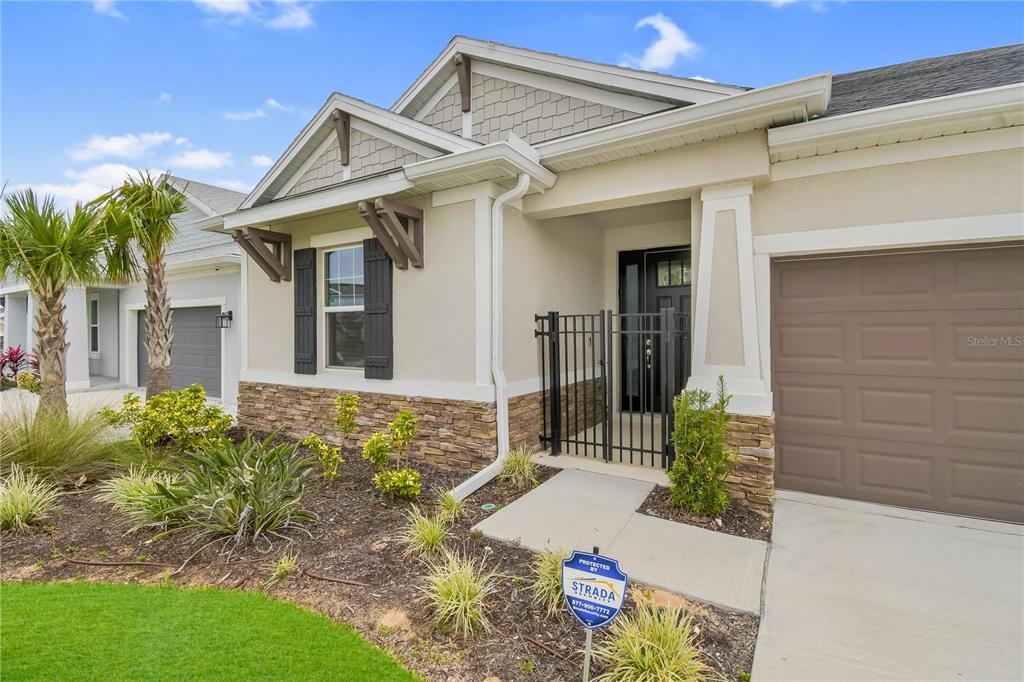 A tan house exterior features a stone facade, a black metal gate, and a garage — 1224 WATERVIEW RIDGE CIRCLE, APOPKA, FL