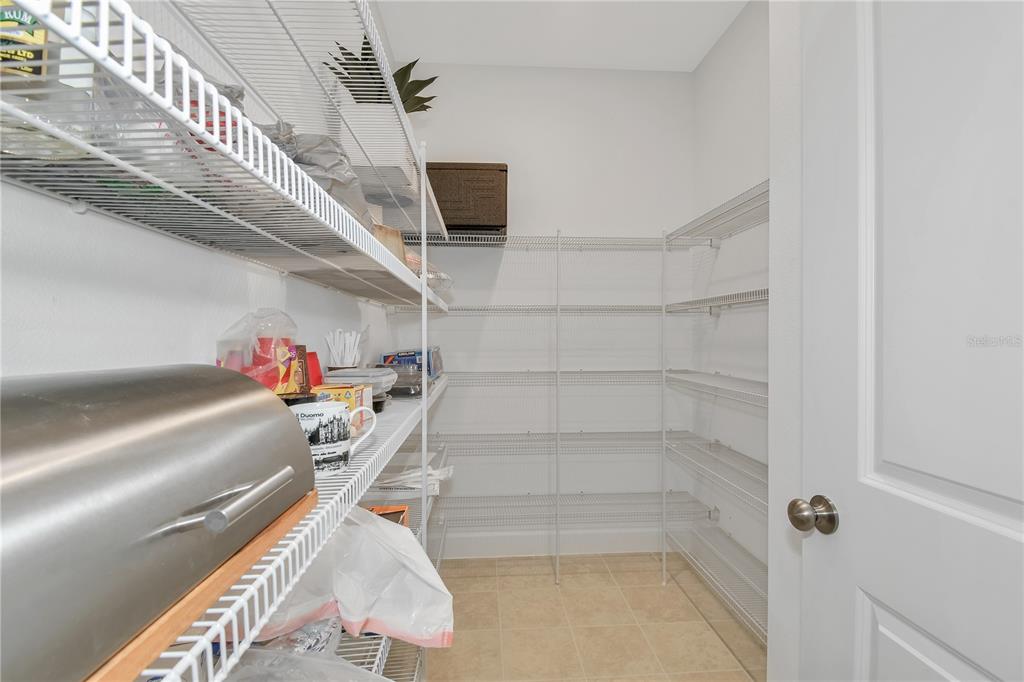 A walk-in pantry features white wire shelving, light tile flooring, and a white door — 1224 WATERVIEW RIDGE CIRCLE, APOPKA, FL