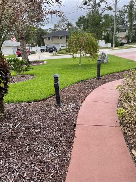 A paved walkway winds through a landscaped yard with mulch beds and outdoor lighting — 19 SANCHEZ AVENUE, ORMOND BEACH, FL