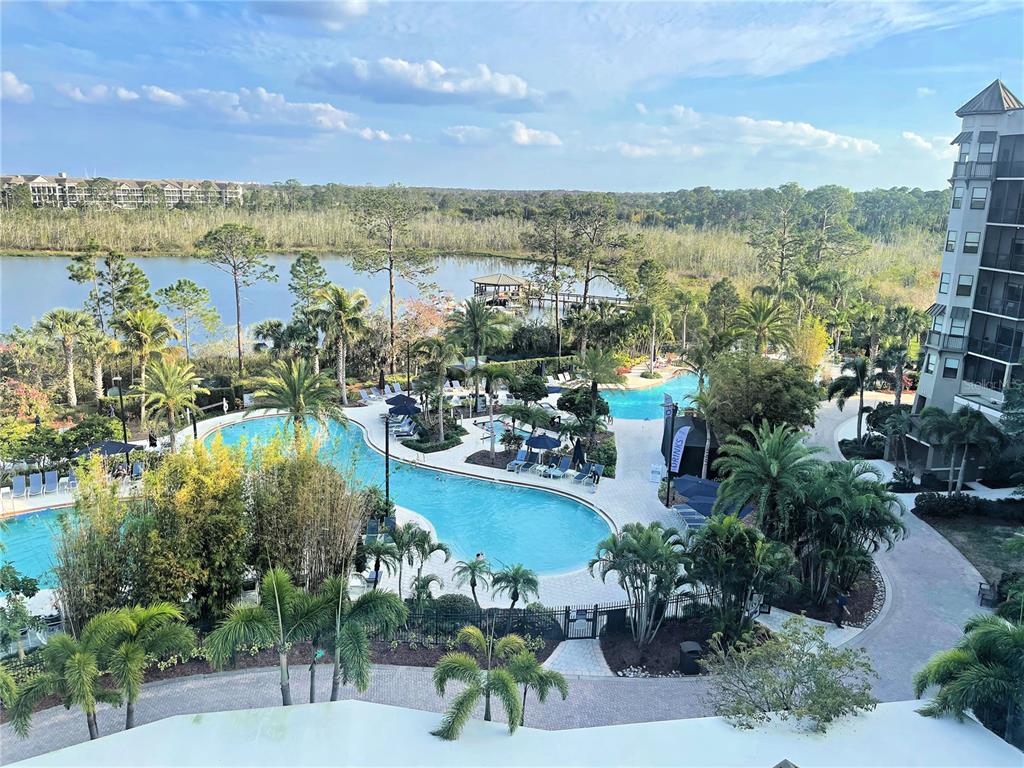 A gated entrance with a small guardhouse, palm trees, and a paved driveway — 14501 GROVE RESORT AVE UNIT 1622, WINTER GARDEN, FL