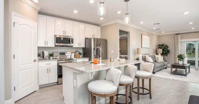 A modern kitchen features white cabinets, granite countertops, and a breakfast bar with stools — 17625 NW 168TH ROAD, ALACHUA, FL