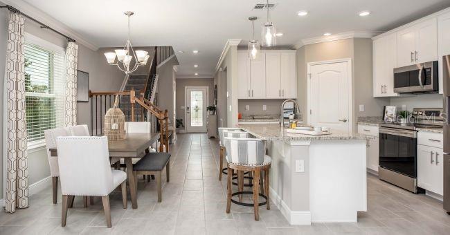 An open-concept kitchen and dining area features white cabinets, granite countertops, and tile flooring — 17625 NW 168TH ROAD, ALACHUA, FL