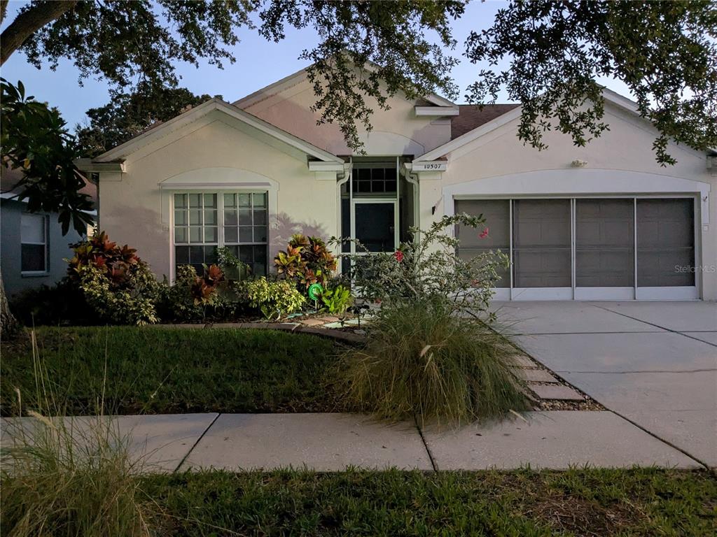 A single-story house with a beige stucco exterior, a two-car garage, and a landscaped front yard — 10507 WALKER VISTA DRIVE, RIVERVIEW, FL