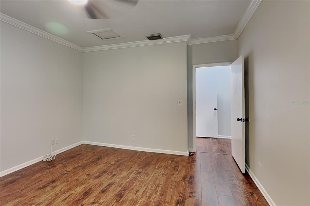 An empty room features light gray walls, crown molding, and dark wood-look flooring — 3801 1/2 W PALMIRA AVENUE, TAMPA, FL