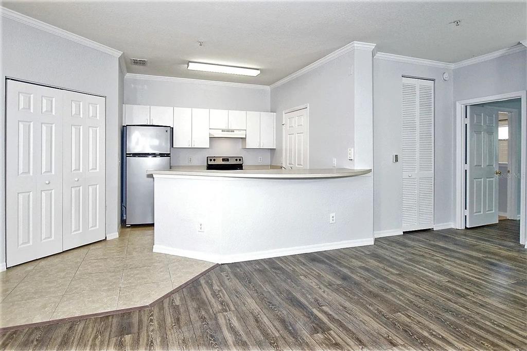 A kitchen with white cabinets, a breakfast bar, and wood-look flooring in an open room — 3615 CONROY ROAD UNIT 612, ORLANDO, FL