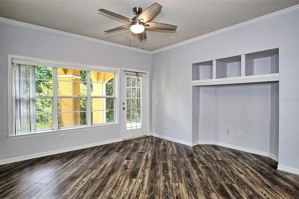 An empty room features wood-look flooring, a ceiling fan, a glass door, and built-in shelving — 3615 CONROY ROAD UNIT 612, ORLANDO, FL