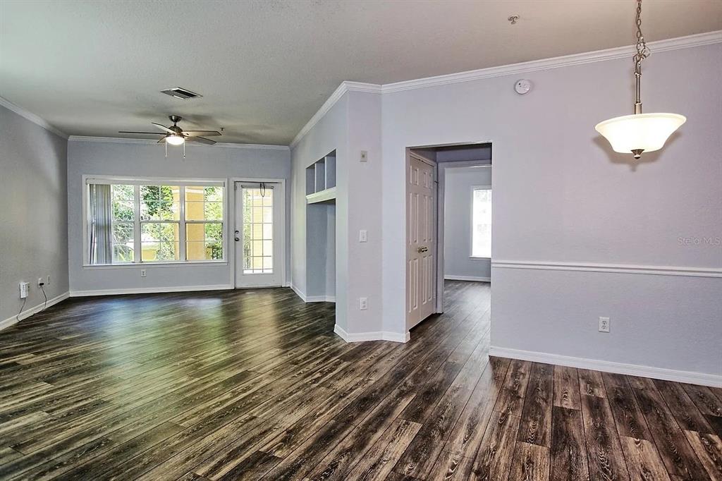 A living and dining area with light gray walls, wood-look flooring, and a ceiling fan — 3615 CONROY ROAD UNIT 612, ORLANDO, FL