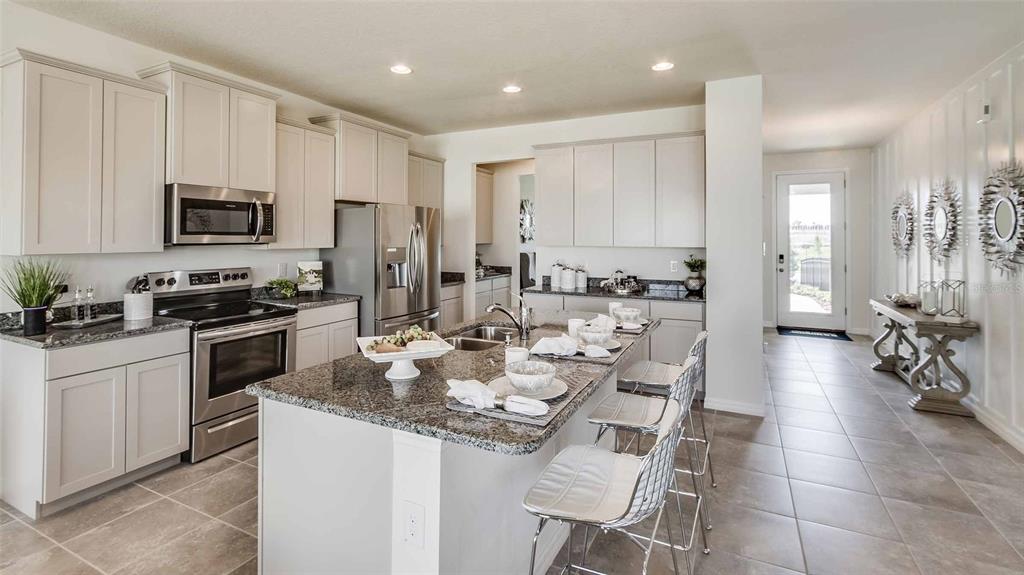 A kitchen with light-colored cabinets, granite countertops, a center island, and tile flooring — 17119 JAMES TRAIL, PARRISH, FL