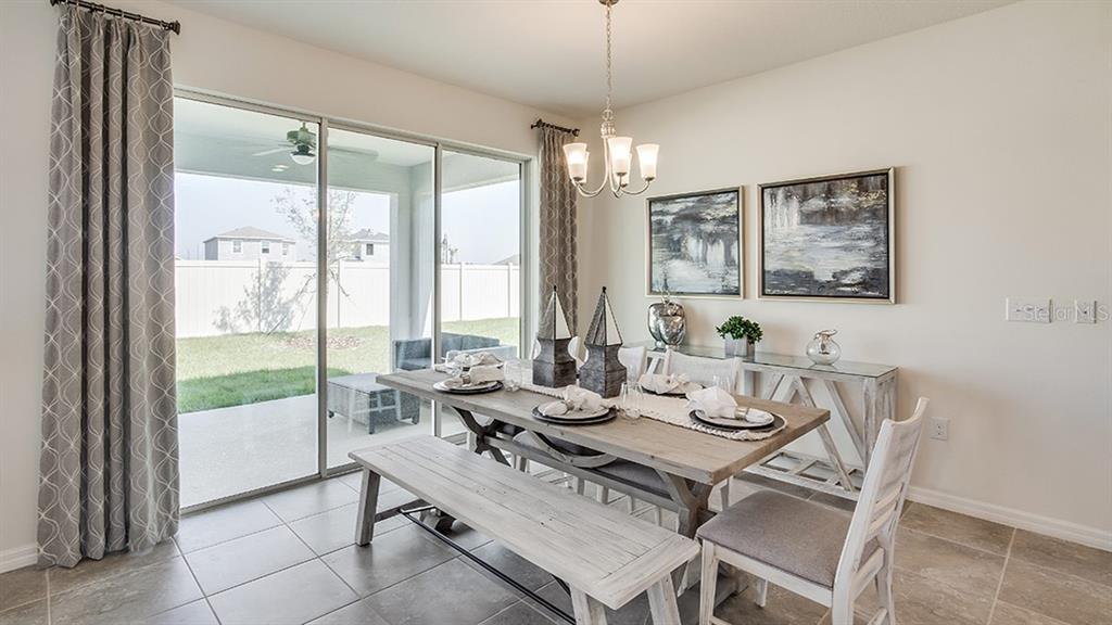 A dining room with a wooden table, bench, chairs, and sliding glass doors to a patio — 17119 JAMES TRAIL, PARRISH, FL