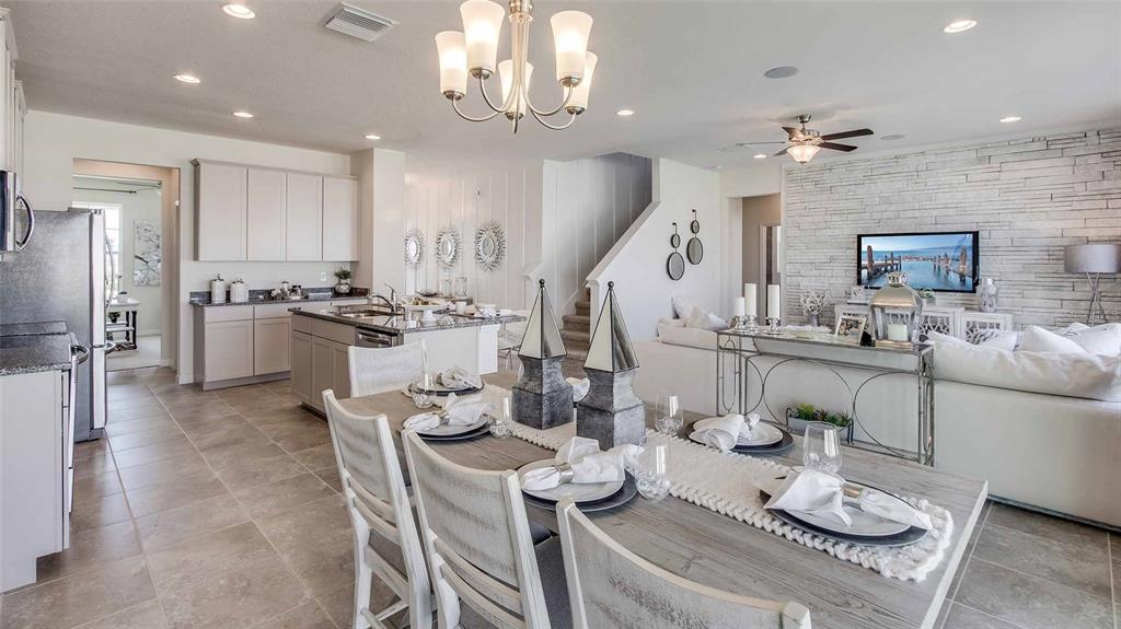 An open-concept dining area features a wooden table, light-colored cabinetry, and a stone accent wall — 17119 JAMES TRAIL, PARRISH, FL