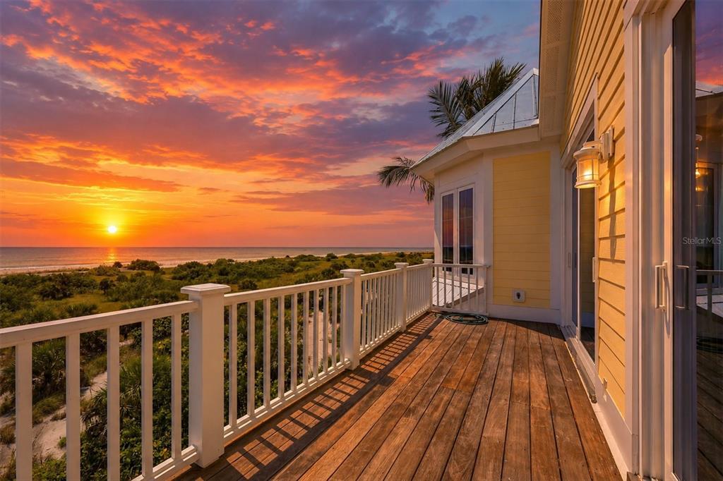 A wooden deck with a white railing overlooks a beach at sunset — 7394 PALM ISLAND DRIVE, PLACIDA, FL