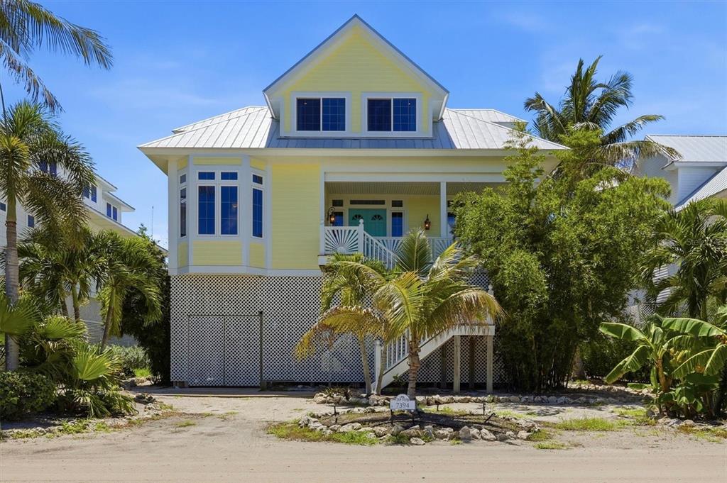 A yellow elevated house with a metal roof, white lattice skirting, and a front staircase — 7394 PALM ISLAND DRIVE, PLACIDA, FL