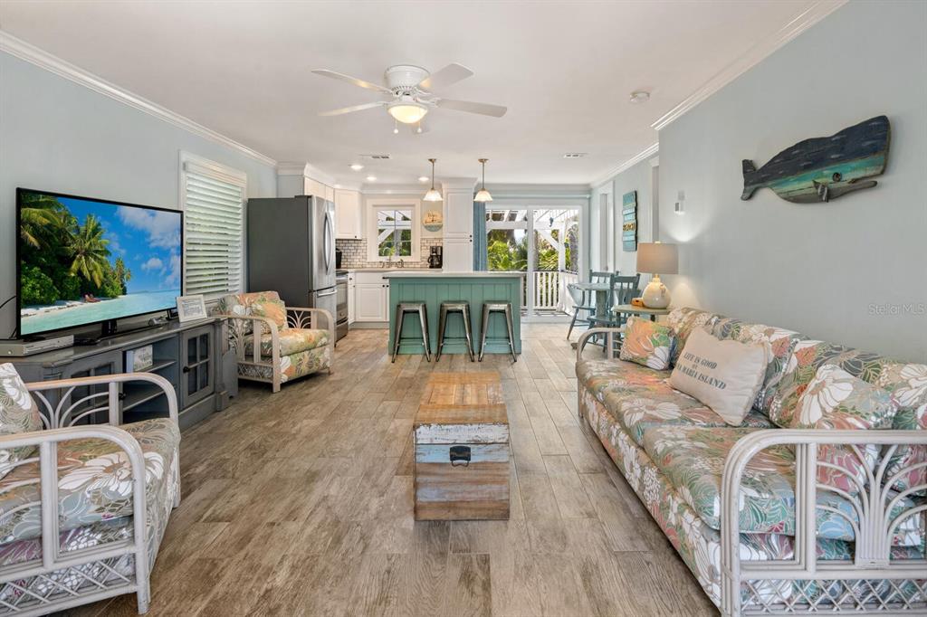 A living room with light blue walls, floral furniture, a wooden coffee table, and kitchen island — 305 57TH STREET UNIT B, HOLMES BEACH, FL